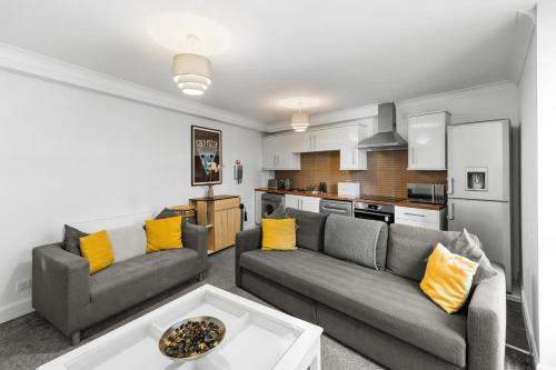 a living room with two couches and a kitchen at Commercial Street Residence in Dundee