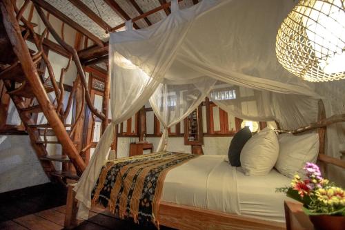 a bedroom with a bed with a canopy at The Calmtree Bungalows in Canggu