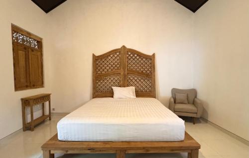 a bedroom with a bed with a wooden headboard and a chair at Omah Ndoro Sugih in Serut