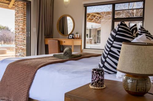 a bedroom with a bed and a table with a lamp at Afrikaya Villas in Hoedspruit