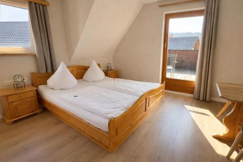 a bedroom with a bed with white sheets and a window at Pension Bergseeblick in Titisee-Neustadt