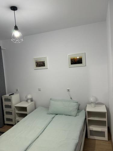 a white bedroom with a bed and two night stands at Central Apartment in Zalău