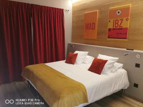 a bedroom with a bed with two red pillows at World Hotel in Saint-Vulbas
