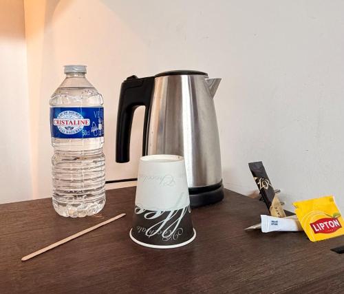 a bottle of water sitting next to a coffee pot and a bottle of water at Bio-Motel in Saint-Vulbas