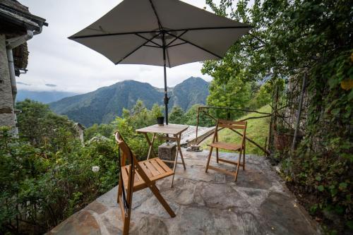 a table and two chairs with an umbrella at Walser House in Rimella