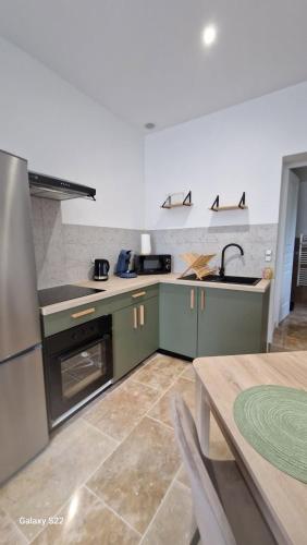 a kitchen with green cabinets and a stainless steel refrigerator at Gîte pour 2 personnes in Le Bugue