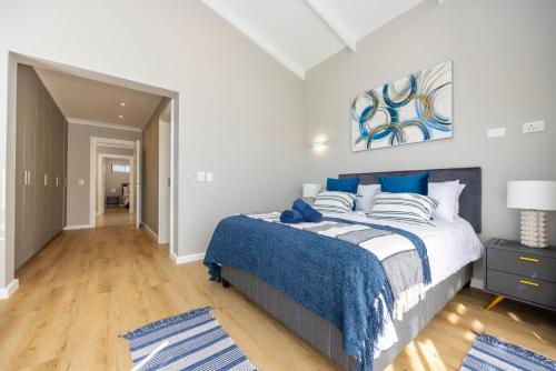 a bedroom with a large bed with blue pillows at Nova Haus in Plettenberg Bay