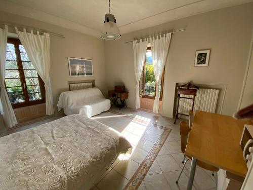 a bedroom with a bed and a desk and windows at Le Colombier d'Antan in Les Vans