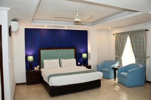 a bedroom with a large bed and a blue wall at Royalton Hotel Rawalpindi in Rawalpindi