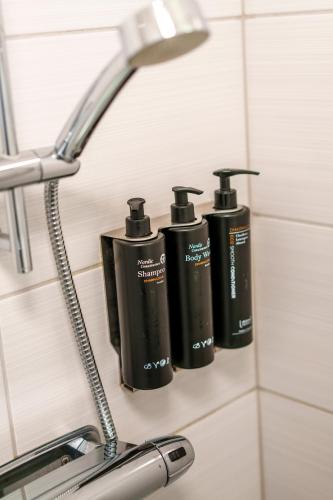 three black bottles on the wall of a bathroom at Best Western Hotel Botnia in Umeå