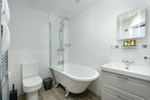 a white bathroom with a tub and a toilet and a sink at 1 Bed in Lowick oc-coq46 in Holburn