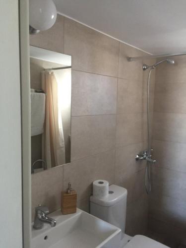 a bathroom with a toilet and a sink and a mirror at Sea Sun Sand in Loutra