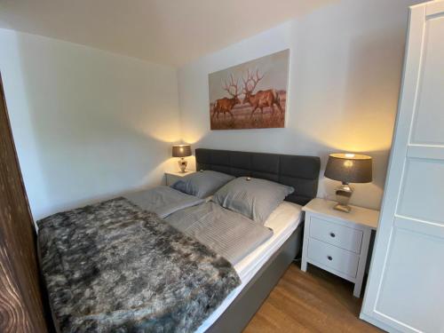a bedroom with a bed and a nightstand with two lamps at Chalet-Apartment Waldfrieden, in ruhiger Lage mit TG in Hahnenklee-Bockswiese