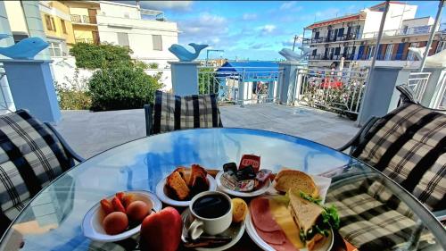 a glass table with a plate of breakfast food on a balcony at Dolphin Hotel in Skopelos Town