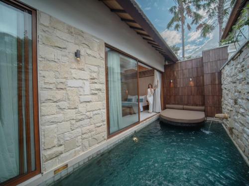 a woman standing next to a pool in a house at La Vie Villa Seminyak by Ini Vie Hospitality in Seminyak