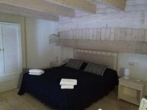 sypialnia z czarnym łóżkiem i dwoma ręcznikami na nim w obiekcie Barko Apartments & Suites w mieście Steccato