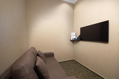 ein Wohnzimmer mit Sofa und Flachbildfernseher in der Unterkunft Hotel Allora in Budapest