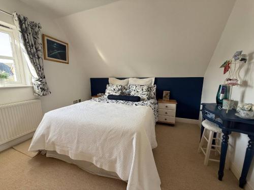 a bedroom with a white bed and a desk at Our Garden View Room in Bedford