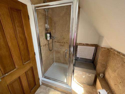 a shower with a glass door in a bathroom at Our Garden View Room in Bedford