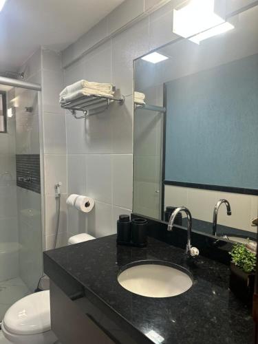 a bathroom with a sink and a toilet and a mirror at Loft 306 Imperial Suites in João Pessoa