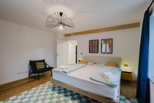 a bedroom with a large white bed and a chair at "Happy Vibes" City Appartment in Passau