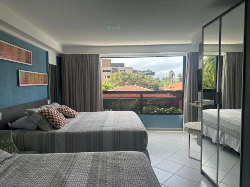 a bedroom with two beds and a large window at Loft 306 Imperial Suites in João Pessoa