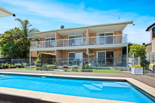 a house with a swimming pool in front of it at Saltwater Villas - Pet Friendly Accommodation in Mooloolaba