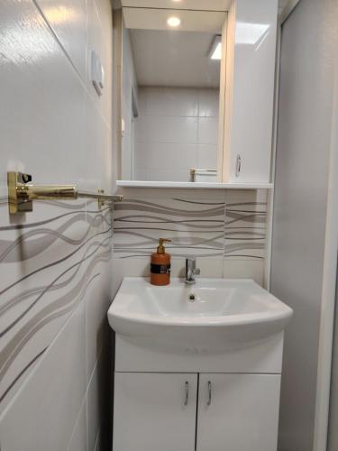 a bathroom with a white sink and white cabinets at Apartman Pavlica in Kragujevac