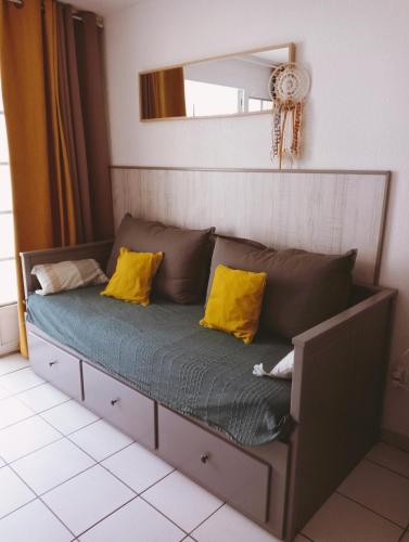 a couch with yellow pillows on it in a room at Appartement Golf et Océan in Moliets-et-Maa