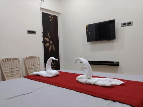 two swans sitting on a bed with a red blanket at SRC Mahal in Killai