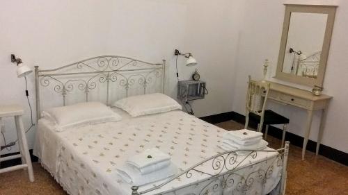 Schlafzimmer mit einem weißen Bett, einem Schreibtisch und einem Spiegel in der Unterkunft A casa di Vivì in Martano