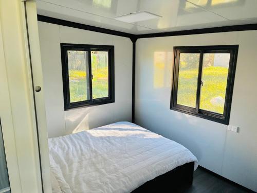 a small bedroom with a bed and two windows at Beautiful Pradise 1 in Penfield