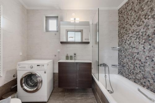 a bathroom with a washing machine and a bath tub at Villa Saktouris in Saktoúria