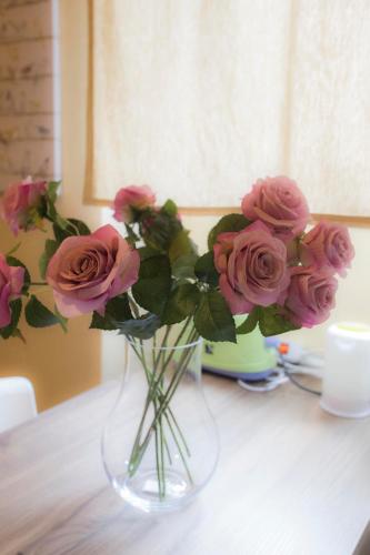 a glass vase filled with pink roses on a table at Stampace Apartments in Cagliari
