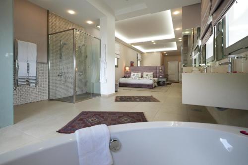 a large bathroom with a tub and a bedroom at Cherry Blossom Boutique Hotel in Bḩamdūn