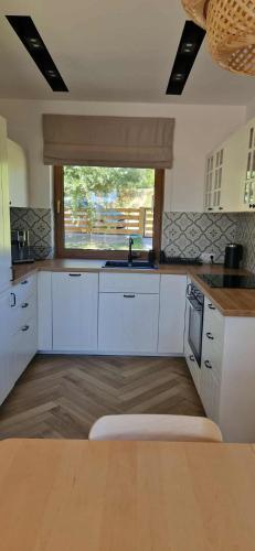 a kitchen with white cabinets and a large window at Wzgórze Wadery Siekierczyna in Siekierczyna