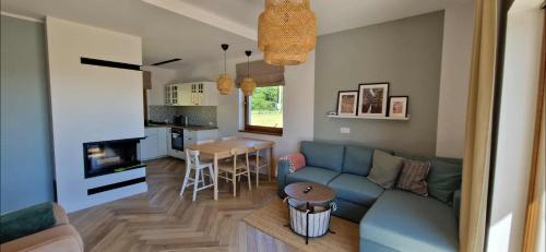 a living room with a blue couch and a kitchen at Wzgórze Wadery Siekierczyna in Siekierczyna