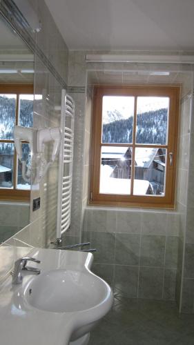 a white bathroom with a sink and a window at Cèsa Raggio di Sole in Arabba