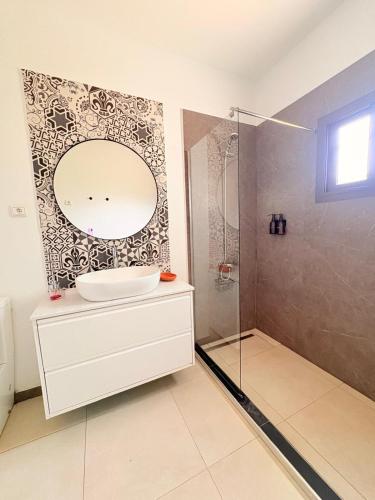 a bathroom with a sink and a shower with a mirror at Villa Le Charme de Somone Piscine privée confort & proximité plage in Somone