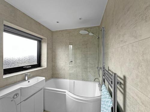 a bathroom with a white tub and a window at Modern Contractor House - Lockable Gated Parking in Kiveton Park