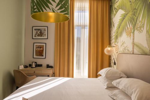 a bedroom with a white bed and a window at Hotel Verlaine in Cannes
