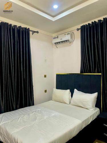 a bed in a room with black drapes at Derucci Luxury Apartment in Owerri