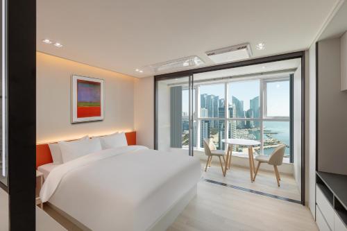 a bedroom with a bed and a balcony with a table at 센텀 뉴시즈 호텔 in Millak-tong