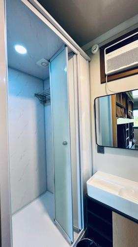 a bathroom with a shower and a sink and a mirror at Duli Beach Farm Hostel in Duli