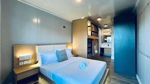 a bedroom with a large white bed with blue pillows at Duli Beach Farm Hostel in Duli