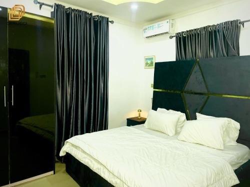 a bedroom with a large white bed with black curtains at Derucci Luxury Apartment in Owerri