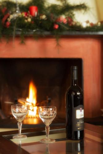 a bottle of wine and two wine glasses in front of a fireplace at B&B Il Trebbio in Corsanico-Bargecchia