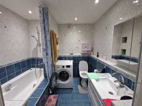 a bathroom with a tub sink and a washing machine at Sitsi apartment in Tallinn