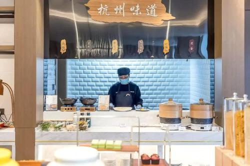 a chef in a kitchen wearing a mask at Atour Hotel Zhijiang Bridge in Hangzhou