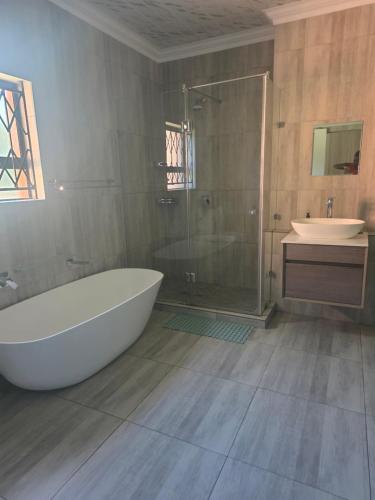 a bathroom with a tub and a shower and a sink at The Second Tranquilo in Ermelo